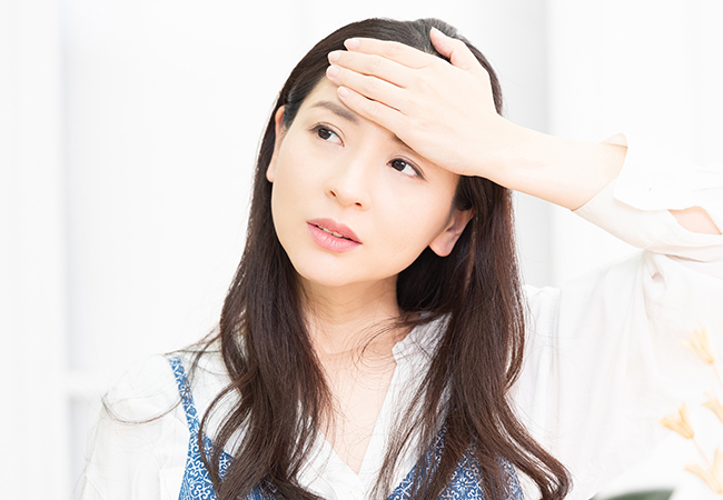 熱があり額に手を当てる女性