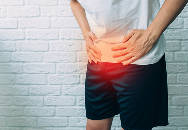 排尿に違和感を感じ下腹部に手を当てる男性