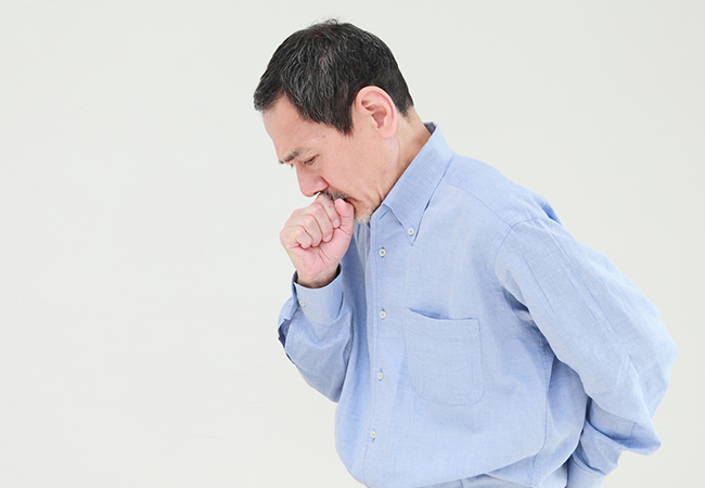 咳き込み手を口元に当てる男性
