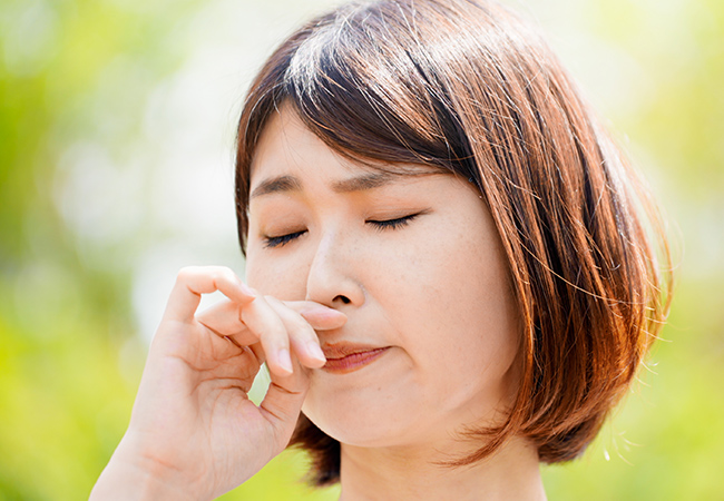 花粉症の症状により鼻の下に手を当てる女性