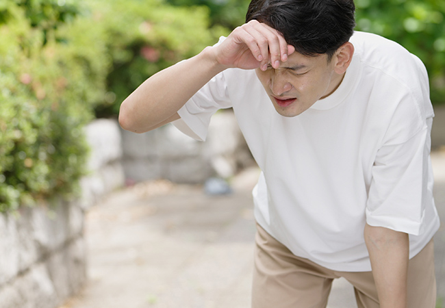 息切れをして額に手を当てる男性